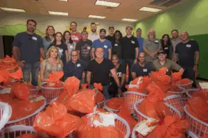 Image of Rod with volunteers in front of tons of gift baskets of food and presents for families during the holidays.