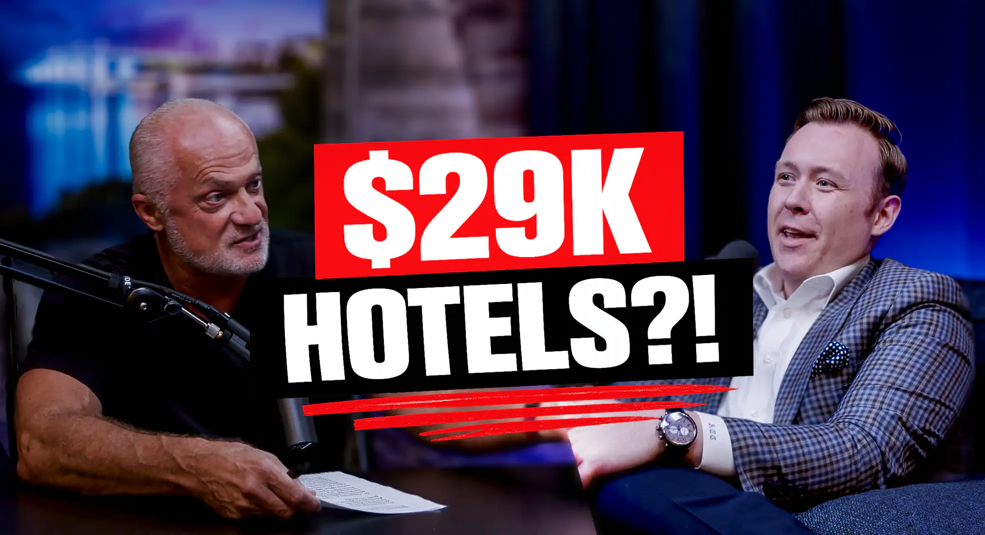 Two men sit at a studio table in a talk-show setting, with a bold red and white overlay displaying '$29K HOTELS?!' across the center.
